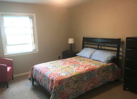 A cozy resident room with a bed and chair