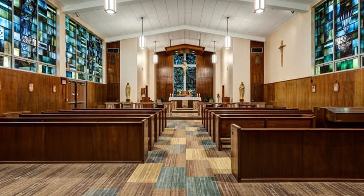 Interior view of the chapel with wooden pews and stained glass windows