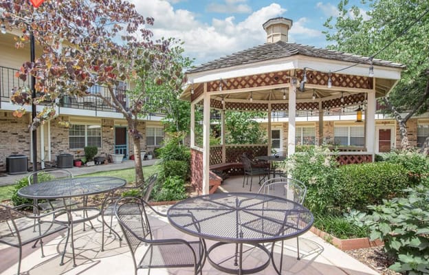 Outdoor gazebo area with seating and green landscaping