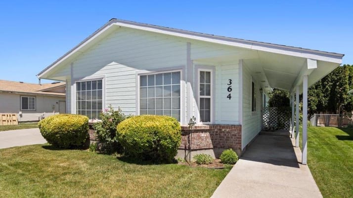 Front view of a light blue home with landscaped bushes