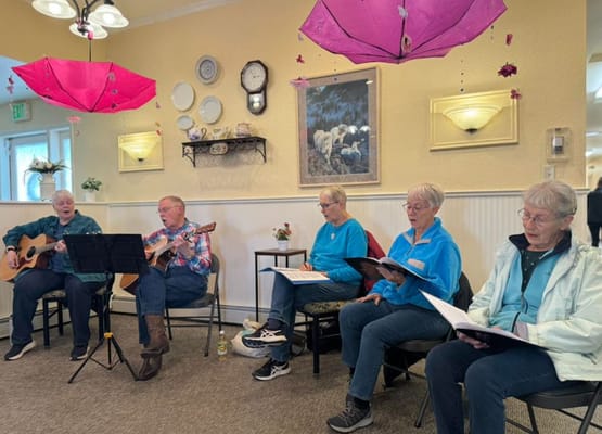Seniors singing and playing guitars in a common area.