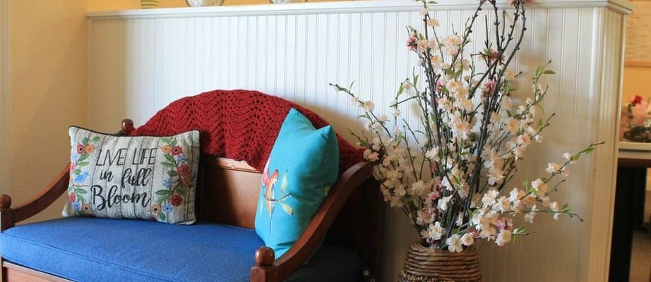 A decorated seating area with colorful pillows and artificial flowers