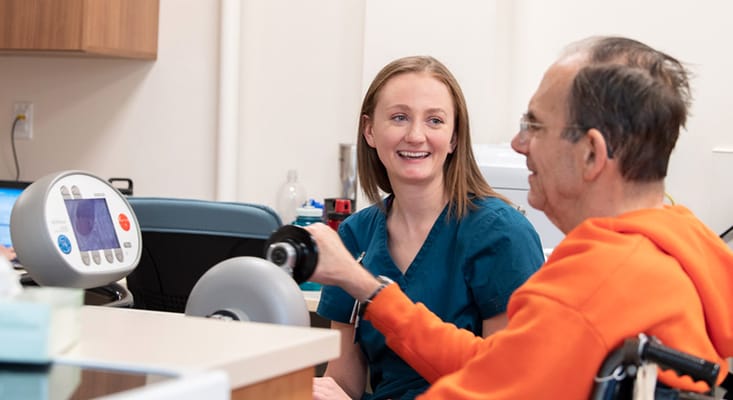 Staff assisting a resident with therapy equipment