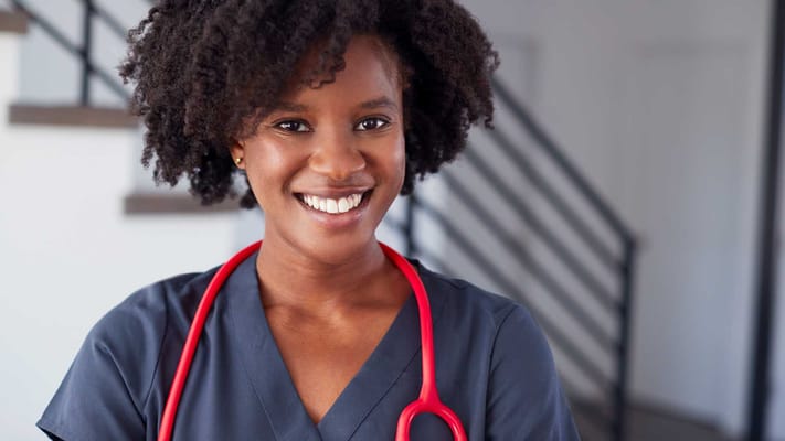 Nurse with curly hair and red stethoscope smiling