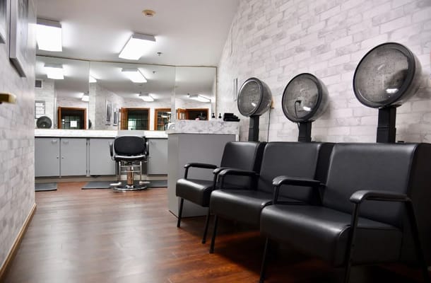 Interior view of the salon with black chairs and hairdryers.