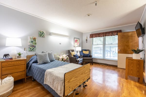 Bright and inviting bedroom with a bed, two armchairs, and a window.