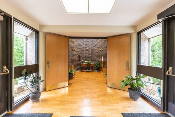 Welcoming entrance with large wooden doors and plants.