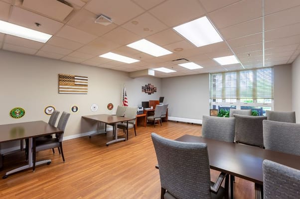 Spacious common area with tables and chairs featuring military decorations.