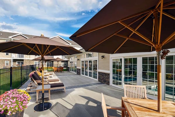 Outdoor patio with umbrellas and seating at Summit At Mill Hill