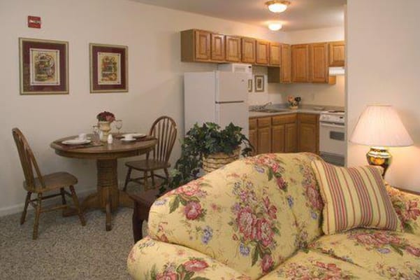 Living room area with a floral couch, dining table, and kitchen in the background