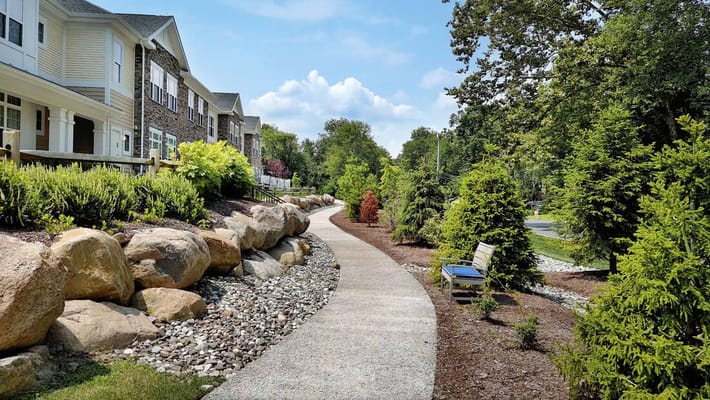 A walkway lined with rocks and greenery at Sunrise of Franklin Lakes.