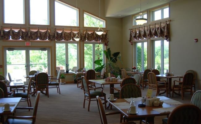 Bright dining room with large windows and tables set for meals.