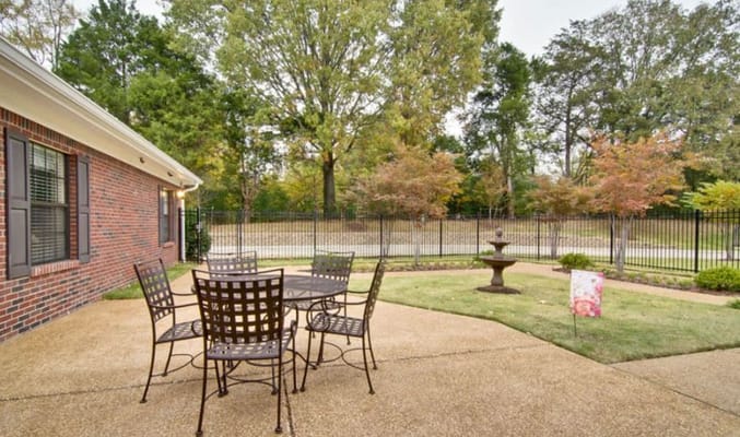 Outdoor seating area with a table and chairs surrounded by trees