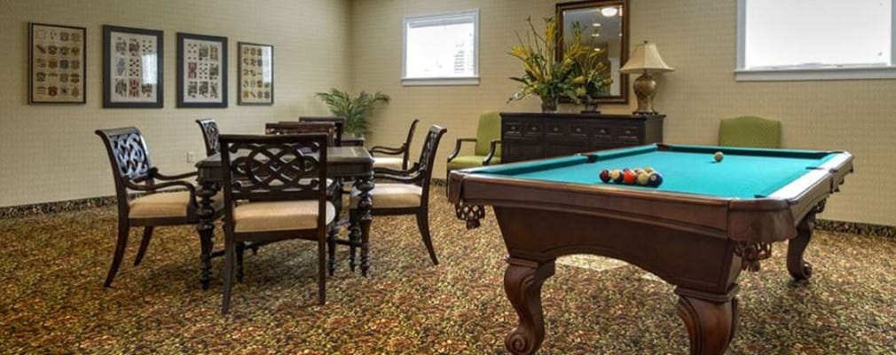 A billiards table with chairs and decorative elements in a senior living facility.