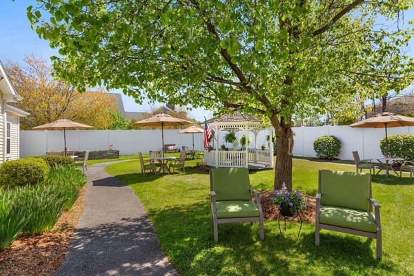 Sunny garden area with chairs, gazebo, and umbrellas