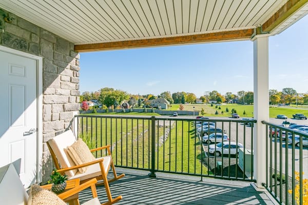 A peaceful balcony with chairs overlooking a green landscape.