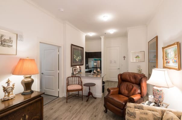 A cozy living area with a leather armchair, lamp, and kitchen area visible.