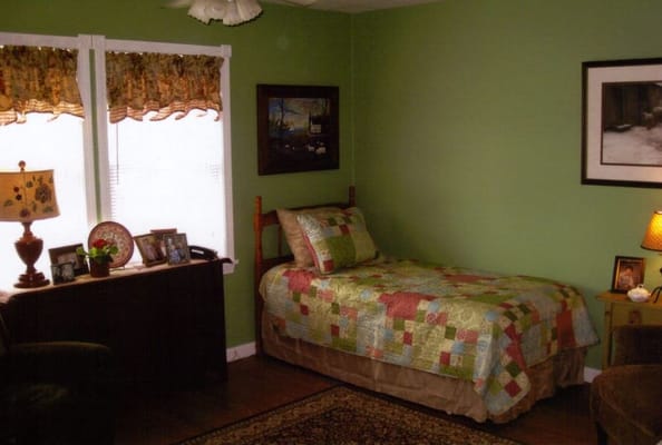 Well-decorated bedroom with green walls and a patchwork quilt