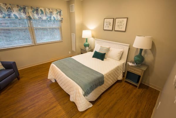 A well-lit bedroom with a single bed, desk, and a comfy sofa.