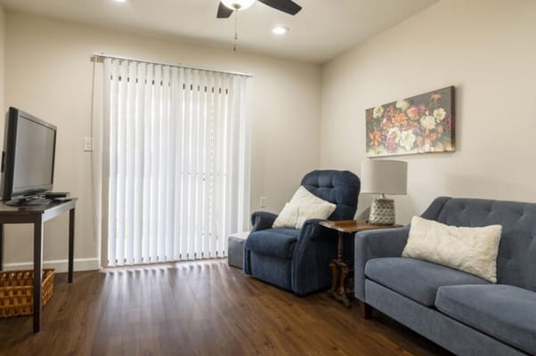 A cozy living room with a blue recliner, grey sofa, and TV.