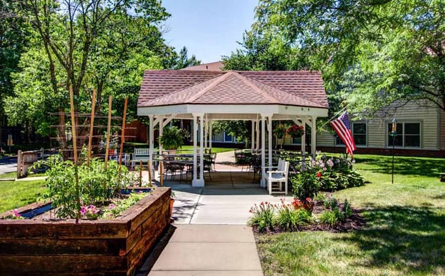 A sunny outdoor gazebo with seating and flowers