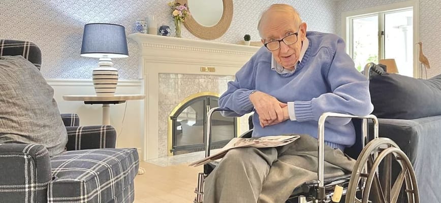 Senior resident in a wheelchair reading a magazine indoors