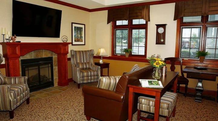 Lounge with armchairs, a fireplace, and a table with flowers