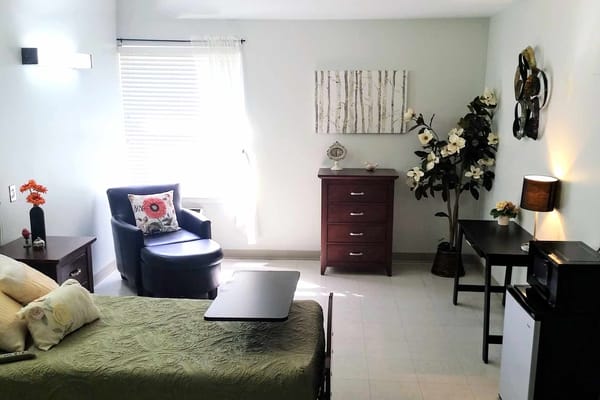 Cozy private room featuring a bed, chair, and decorative elements.