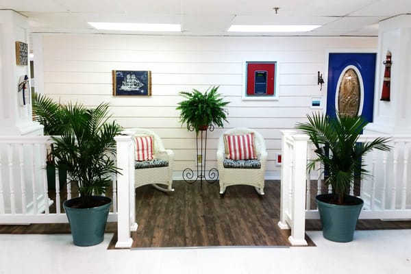 A cozy lobby with wicker chairs, plants, and decorative art