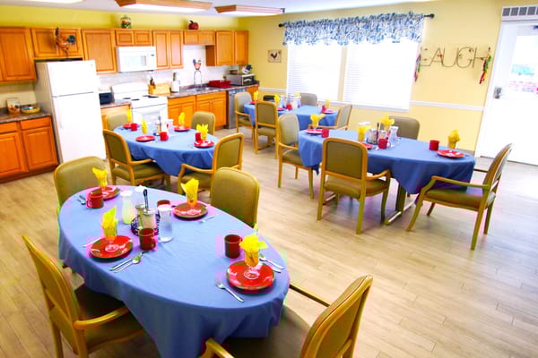 Dining area with blue tablecloths, red plates, and yellow napkins