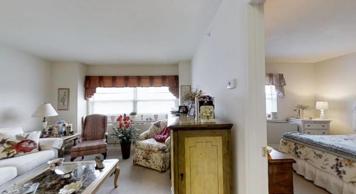A cozy living space with a comfortable seating area, a floral armchair, and natural light from the window.