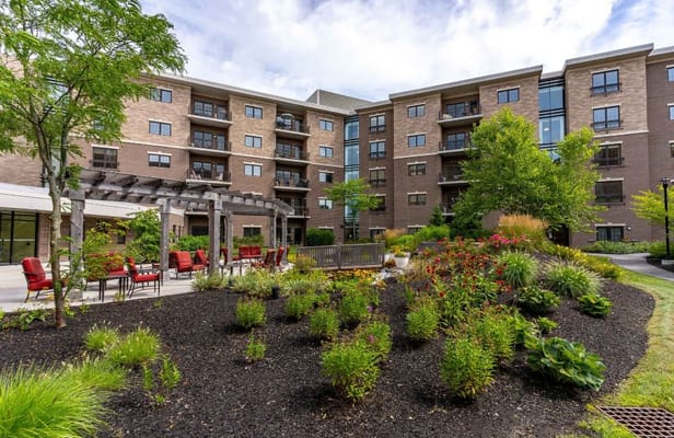 A well-maintained garden with seating area in front of The Park Danforth.