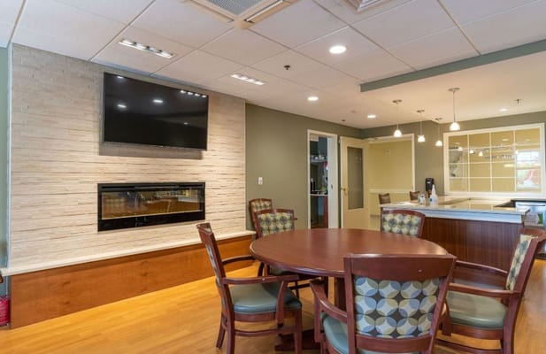 Lounge area with a round table, chairs, and a television.