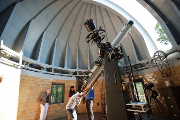 Residents observing through a large telescope in an observatory.