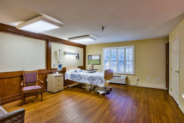 Interior of a private resident room with a single bed and chair