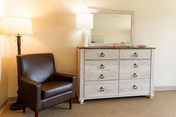 Cozy living room setup with a chair, dresser, and lamp