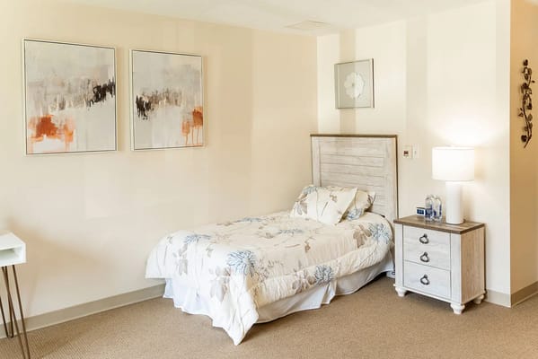 A well-decorated bedroom with a bed, nightstand, and wall art.