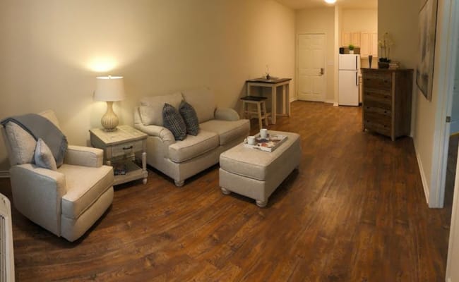 Spacious living room with two chairs, a couch, and a small table