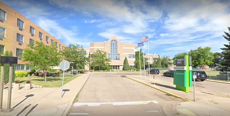Exterior view of Trinity Homes entrance with greenery and flags.