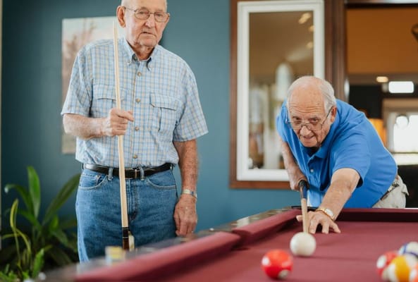 Two residents playing billiards in a common area