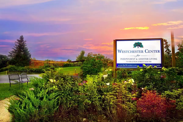 Sign of Westchester Center for Independent & Assisted Living surrounded by flowers