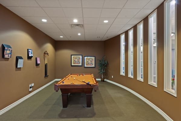 A pool table in the game room with decorative wall art.