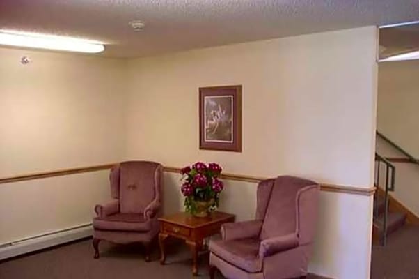 Two plush chairs and a small table with flowers in a lounge area.