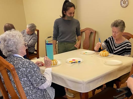 Seniors engaged in an art activity, painting decorative pumpkins.