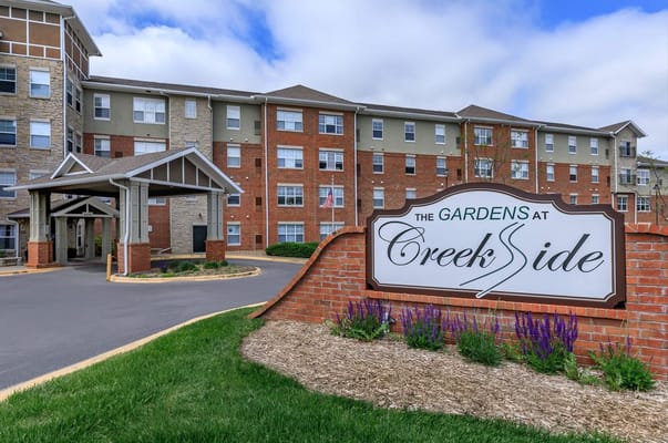 Exterior view of The Gardens at Creekside with sign and flowers