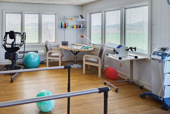 Bright physical therapy room with equipment and seating