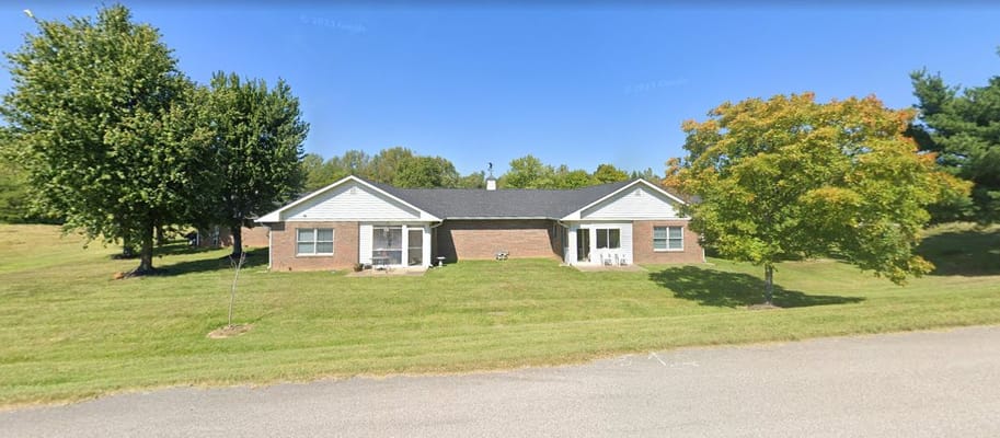 Front view of Maplebrook Village senior living facility surrounded by greenery.