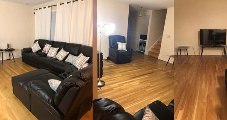 Spacious living room with dark leather sofas and wooden floor