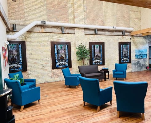 Comfortable common area with blue chairs and stained glass windows