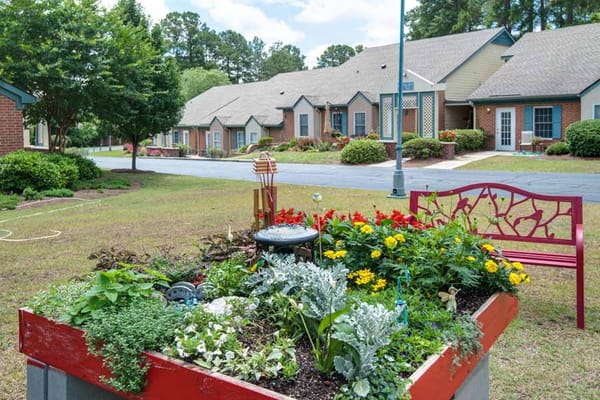 Colorful flower garden with a bench in front of residential buildings.